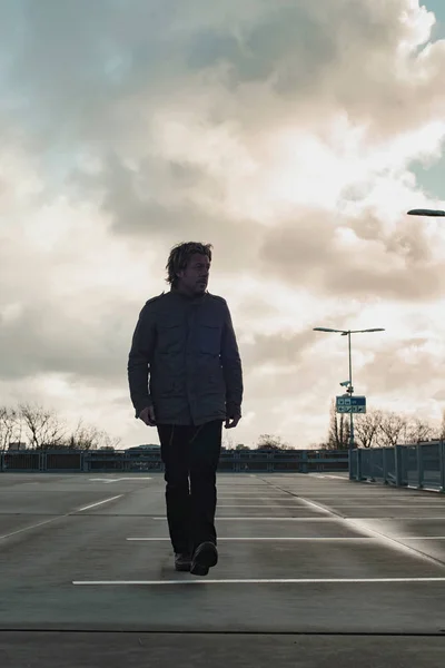 Man inspecting parking lot with cloudy sky. — Stockfoto