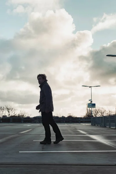 Man inspecting parking place with cloudy sky. Rear view. — Stockfoto