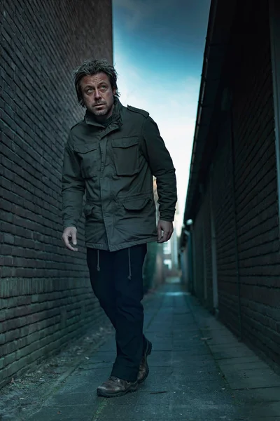 Suspicious man walking in dark urban alley. — Stockfoto