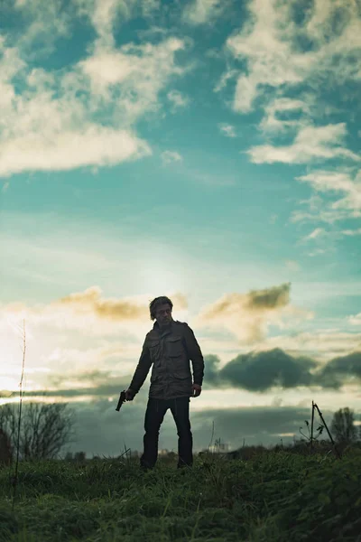 Man met pistool op het platteland bij zonsondergang. — Stockfoto