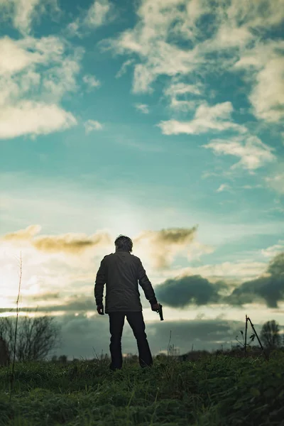 Homme avec arme de poing à la campagne au coucher du soleil . — Photo