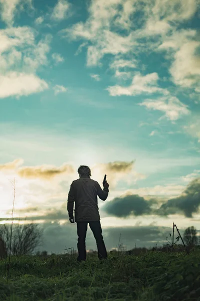 Homme avec arme de poing à la campagne au coucher du soleil . — Photo