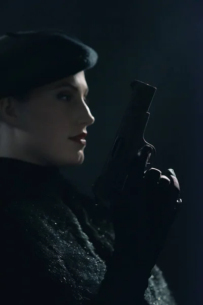 Vintage 1940s woman in beret holding pistol. Side view. — Stock Photo, Image