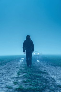 Siyah ceketli ve pantolonlu bir adam. Çamurlu bir arabada klasik bir araba.