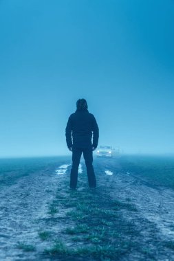 Siyah ceketli ve pantolonlu bir adam. Çamurlu bir arabada klasik bir araba.