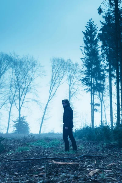 Man in zwart jasje en broek in mistig winterbos. — Stockfoto