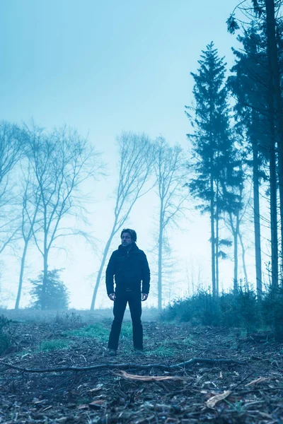 Man in black jacket and trousers in foggy winter forest. — Stock Photo, Image