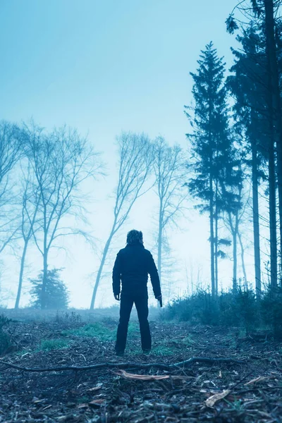 Man in black jacket with gun in foggy winter forest. — Stock Photo, Image