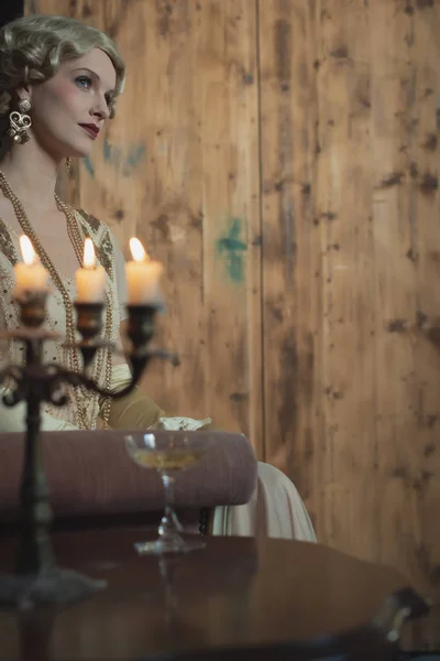 Retro 1920 moda mujer sentado en sofá al lado de la mesa con cand —  Fotos de Stock