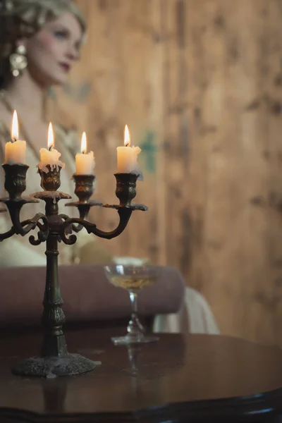 Retro 1920 mode vrouw zitten op de bank naast tafel met cand — Stockfoto