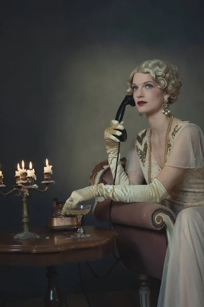 Retro 1920s fashion woman on the phone while sitting on sofa bes — Stock Photo, Image