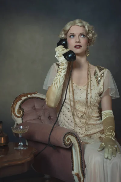 1920 'lerin moda kadını koltukta otururken telefonla konuşuyor. — Stok fotoğraf