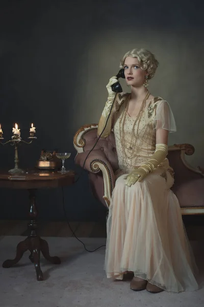 Retro 1920s fashion woman on the phone while sitting on sofa bes — Stock Photo, Image