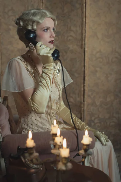 Ρετρό 1920 μόδα γυναίκα στο τηλέφωνο, ενώ κάθεται στον καναπέ bes — Φωτογραφία Αρχείου