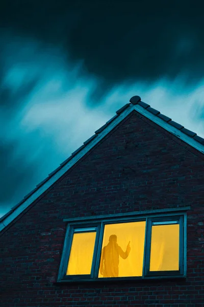 Inbreker met pistool in griezelig huis met verlichte raam onder — Stockfoto