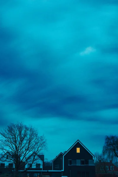 Ominosa casa con ventana iluminada bajo el cielo tormentoso en Twilig — Foto de Stock