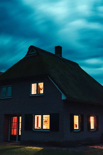 Einbrecher mit Handfeuerwaffe in ominöses Haus mit beleuchteten Fenstern — Stockfoto