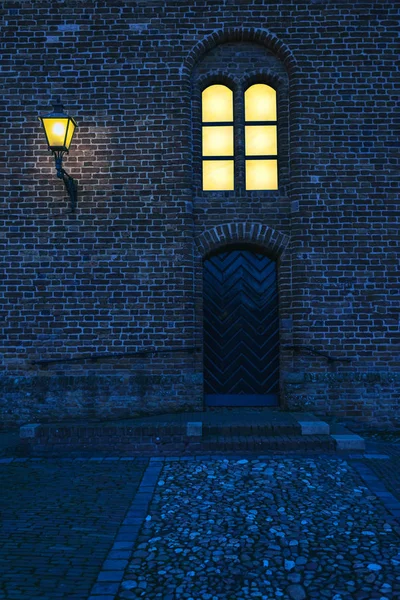 Vieille église avec fenêtre éclairée et lanterne au crépuscule . — Photo