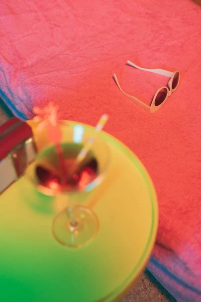 Lunettes de soleil sur chaise longue avec table jaune et cocktail et po — Photo