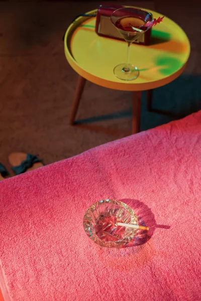 Ashtray with burning cigarette on sunbed with vintage 1950s ladi — Stockfoto