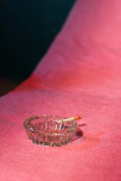 Ashtray with burning cigarette on sunbed with pink towel. — Stock Photo, Image