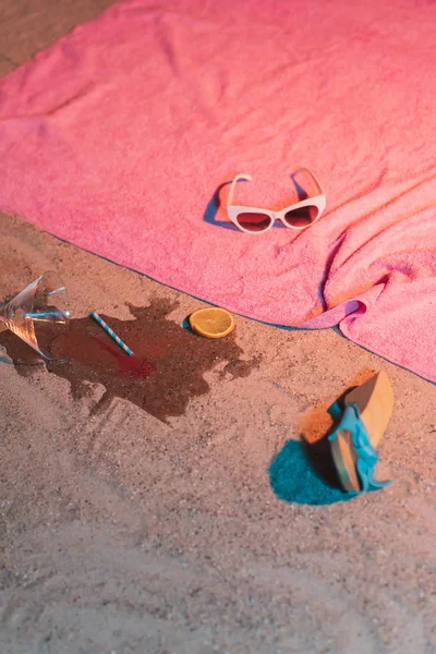 Fallen cocktail glass and vintage ladies shoe next to pink towel — Stock Photo, Image