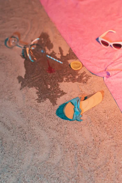Fallen cocktail glass and vintage ladies shoe next to pink towel — 스톡 사진
