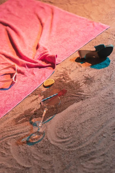 Падшие коктейльные бокалы и винтажные женские туфли рядом с розовым полотенцем — стоковое фото
