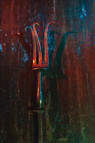 Old bent meat fork on scratched wooden table. — Stock Photo, Image