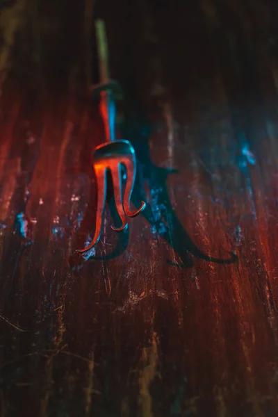 Old bent meat fork on scratched wooden table. — Stock Photo, Image