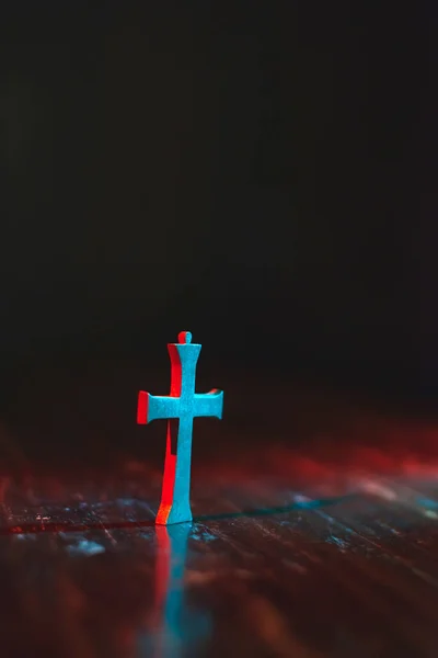Vieux petit crucifix sur table en bois en lumière rouge et bleue au nig — Photo