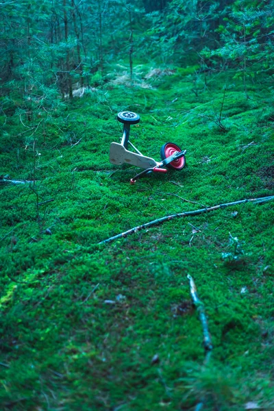 Crianças abandonadas triciclo em solo musgoso na floresta de abetos . — Fotografia de Stock