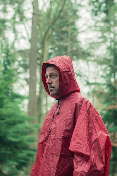 Człowiek w czerwonym płaszczu przeciwdeszczowym w lesie. — Zdjęcie stockowe