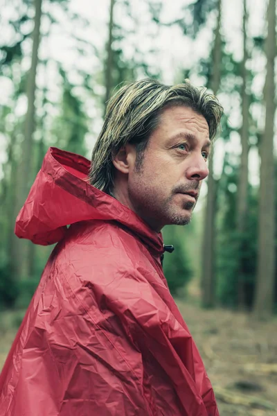Man in rode regenjas in het bos. Zijaanzicht. — Stockfoto
