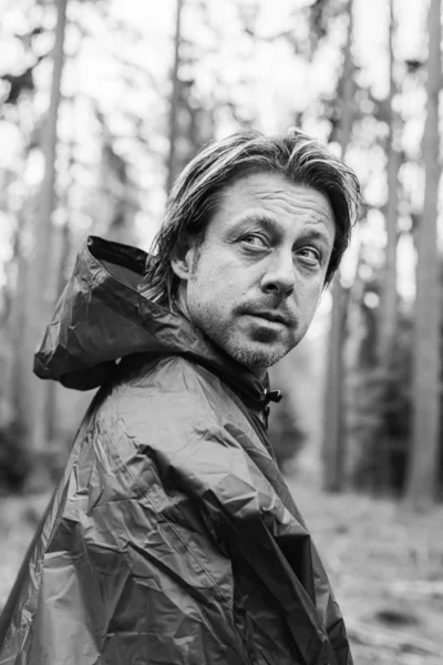 Man in raincoat in woodland. Black and white photography.