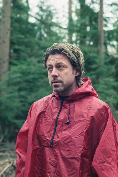 Middle aged man in red raincoat in forest. — Stock Photo, Image