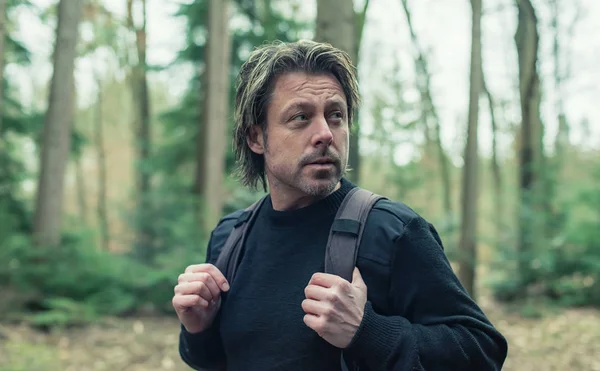 Hombre en suéter de lana negro y mochila senderismo en el bosque . —  Fotos de Stock