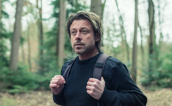 Mannen i svart ylletröja och ryggsäck vandring i skogen. — Stockfoto