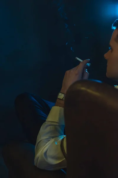Retro fashion man smokes a cigarette and is sitting in leather a — 图库照片