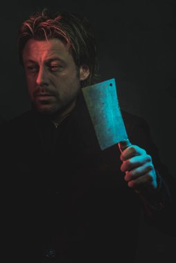 Threatening man with cleaver in hand illuminated by red and blue