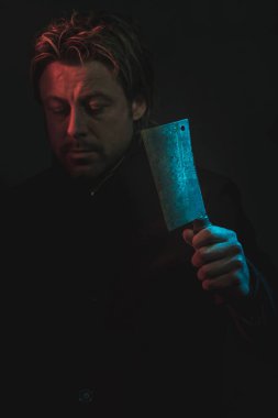 Threatening man with cleaver in hand illuminated by red and blue