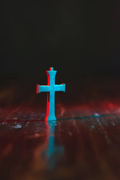 Vieux petit crucifix sur table en bois en lumière rouge et bleue au nig — Photo