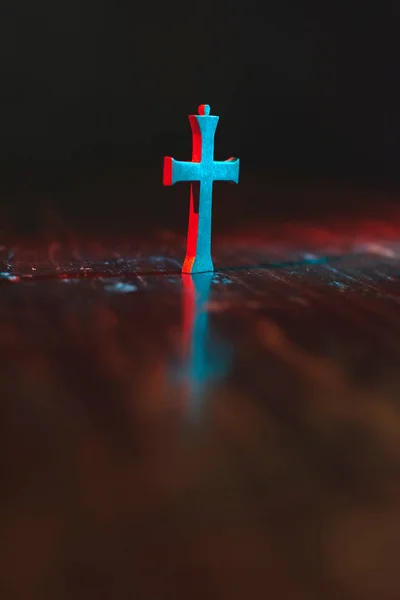 Vieux petit crucifix sur table en bois en lumière rouge et bleue au nig — Photo