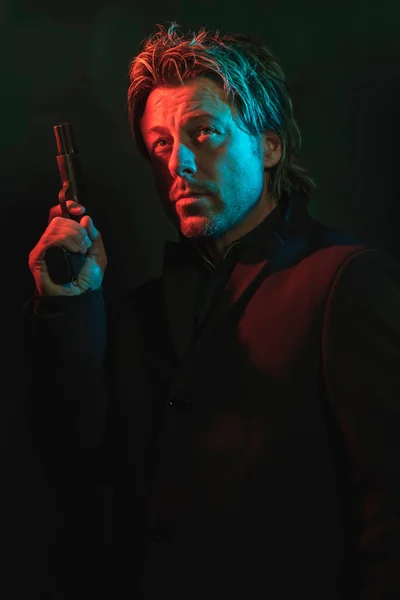 Un hombre sosteniendo una pistola junto a su cabeza. Ilustrado por rojo y azul — Foto de Stock