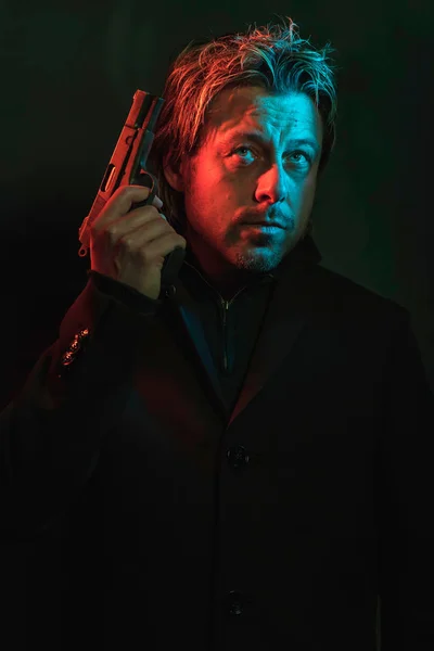 Un uomo che tiene la pistola vicino alla testa. Illminato da rosso e blu — Foto Stock