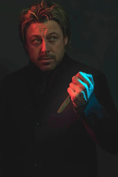 Straszny człowiek z nożyczkami w ręku oświetlony czerwonym i niebieskim ligh — Zdjęcie stockowe