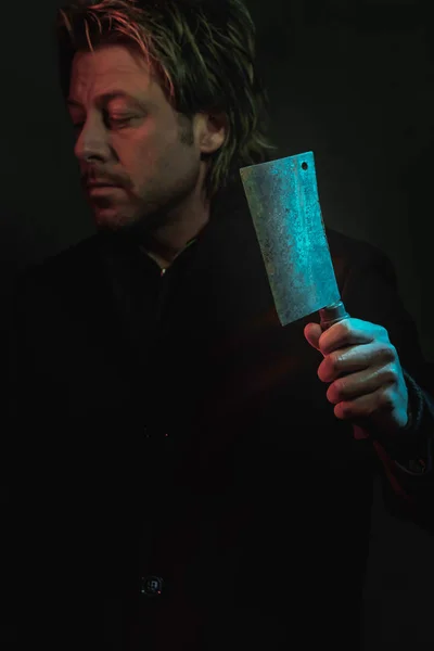 Threatening man with cleaver in hand illuminated by red and blue — ストック写真