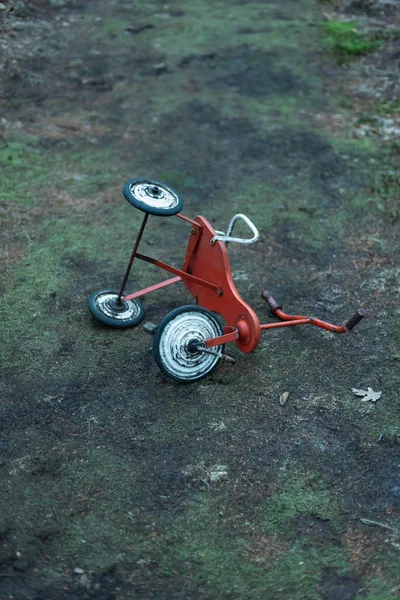 Брошенный трехколесный велосипед, брошенный на лесной тропе . — стоковое фото