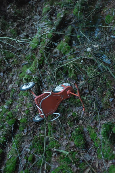 Verlaten driewieler op mossige bosgrond. — Stockfoto