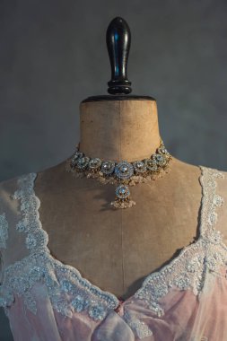 Pembe elbiseli klasik manken büstünde parıldayan kolye..